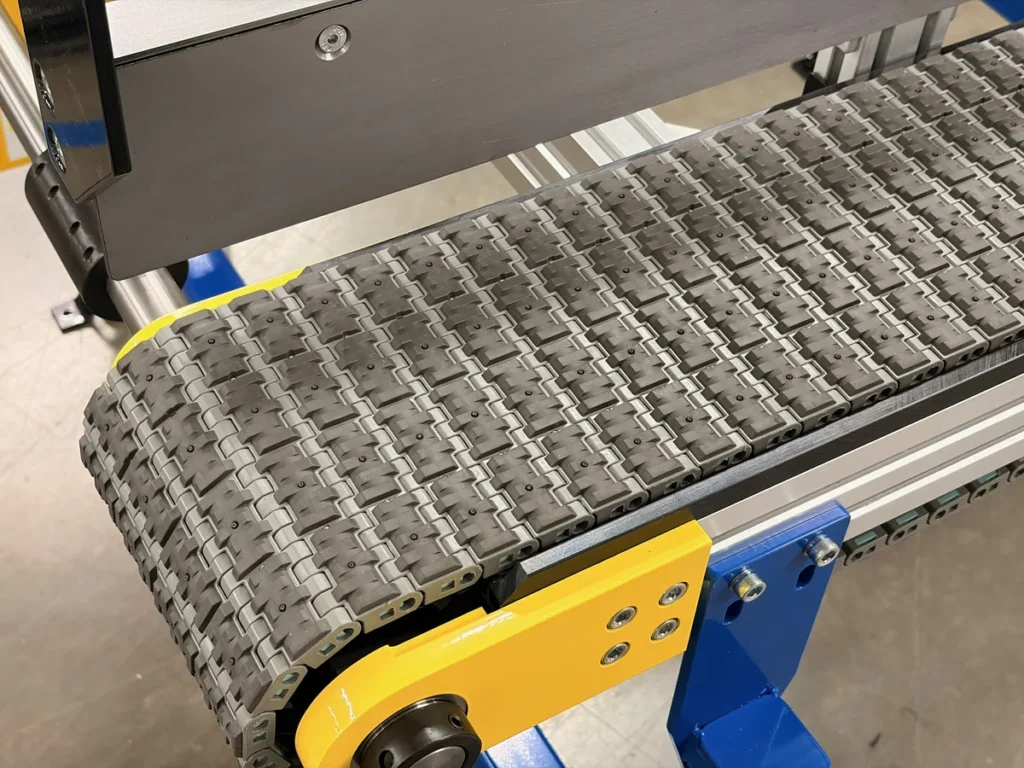 Close-up of high-friction modular plastic belt surface wrapping around end drive for heavy part traction and control