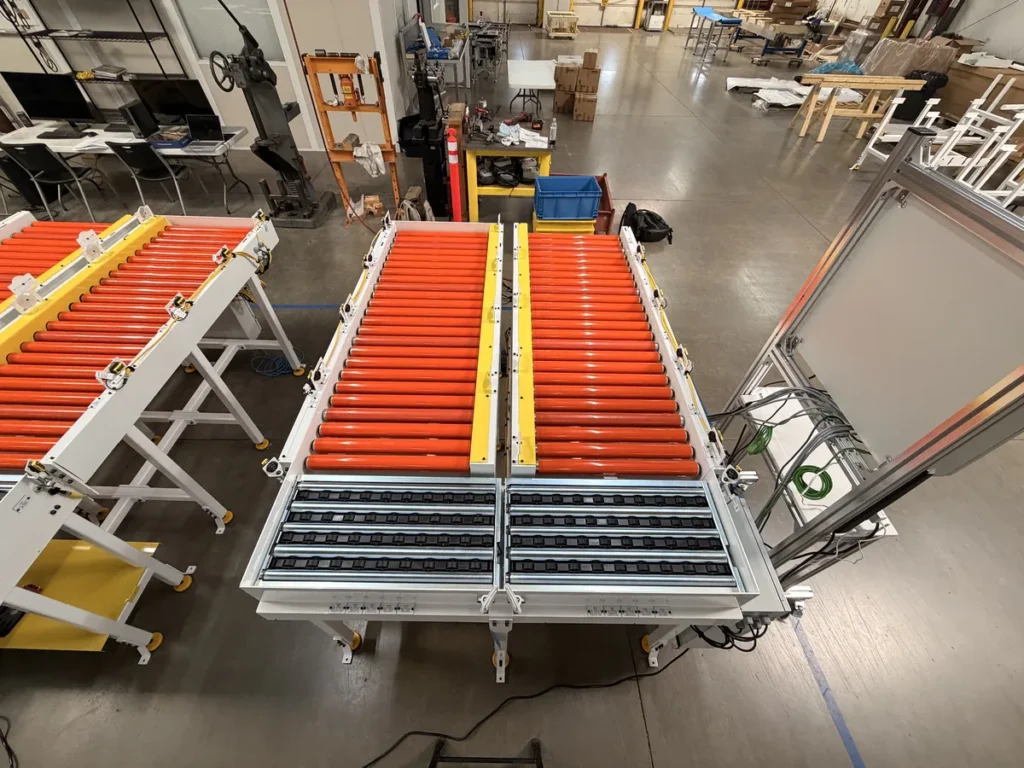 Overhead view of a dual lane roller conveyor pick cell with right angle transfer section and control panel
