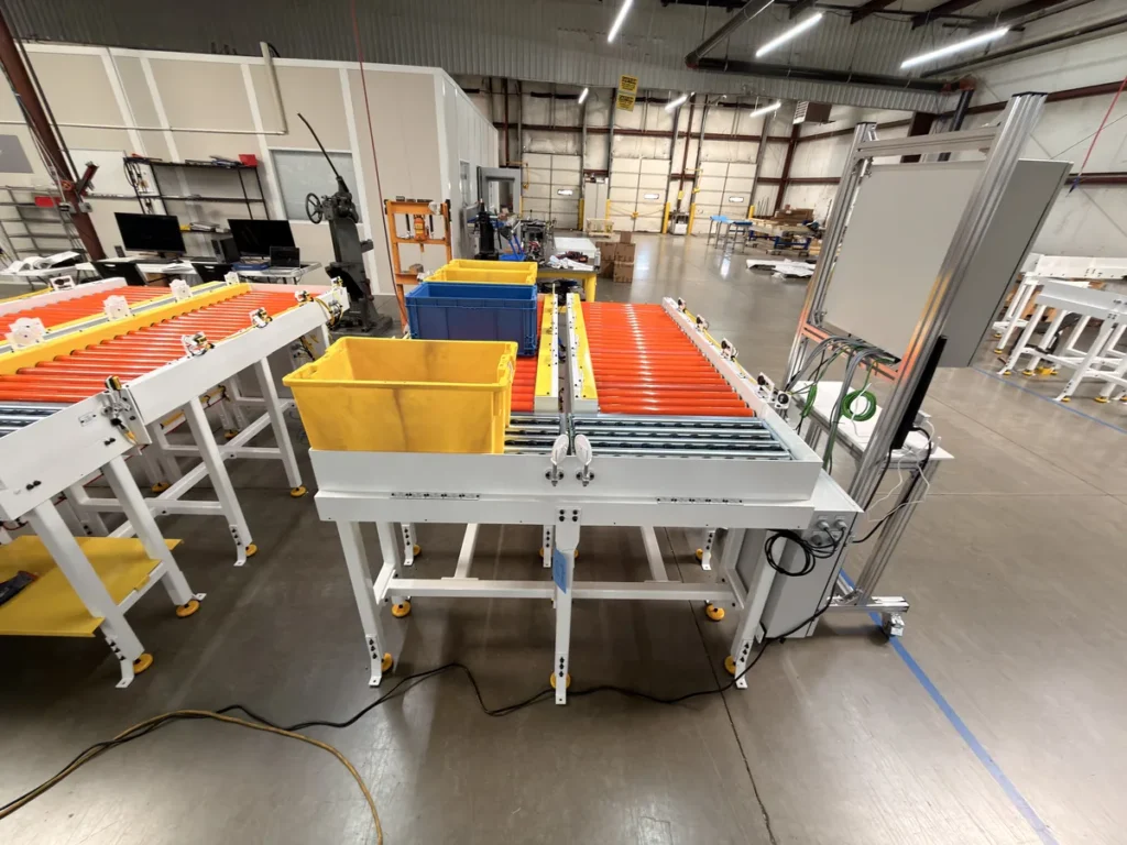 Motor-driven roller tote conveyor pick cell with yellow and blue totes and test panel on the shop floor during factory acceptance testing